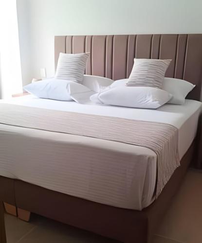 a large bed with white sheets and pillows at Vista impresionante y cama king en Baia Kristal in Los Arrayanes
