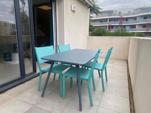 une table bleue et des chaises assises sur un balcon dans l'établissement Villa Bianca Appartement DUPLEX climatisé à 500m de la plage, à Sérignan