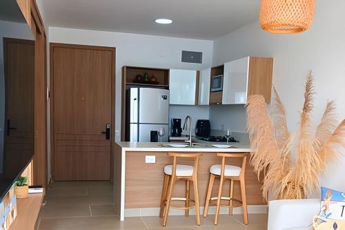 a kitchen with a counter with stools and a refrigerator at Vista impresionante y cama king en Baia Kristal in Los Arrayanes