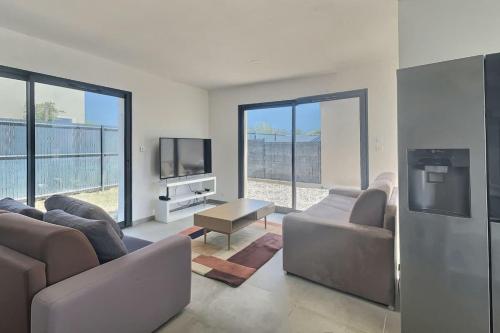 un salon avec des canapés et une télévision à écran plat dans l'établissement Villa climatisée pour 8 personnes avec piscine privée, à Sérignan