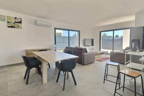 un salon avec une table, des chaises et un canapé dans l'établissement Villa climatisée pour 8 personnes avec piscine privée, à Sérignan