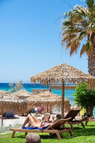a group of people laying on beach chairs under umbrellas at Golden Beach Hotel in Chrissi Akti