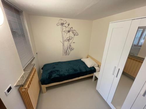 a small bedroom with a bed and a painting on the wall at Lakefront Apartment with Panoramic Pool in Ranzanico