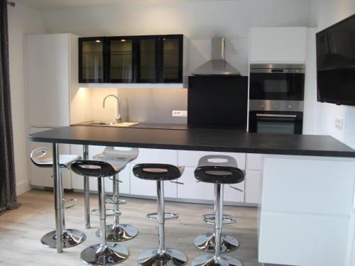 une cuisine avec un comptoir noir et des tabourets dans l'établissement Maison 3 chambres avec terrasse, à Le Touquet-Paris-Plage