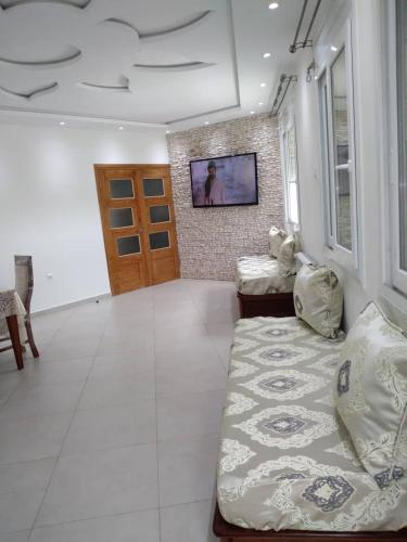 a living room with a bed and a television on a wall at Résidence benidorm in Zeralda