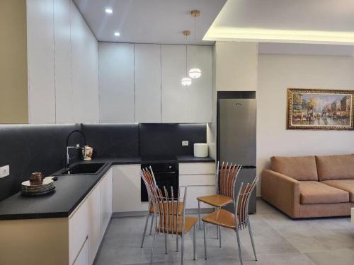 Una cocina con fregadero, sillas y un sofá. en N Luxury Apartment, en Vlorë