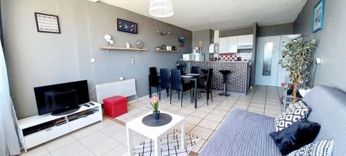 un salon avec un canapé, une table et une télévision dans l'établissement Agreable studio-cabine vue mer 4 personnes à 20 m de la plage, à Valras-Plage