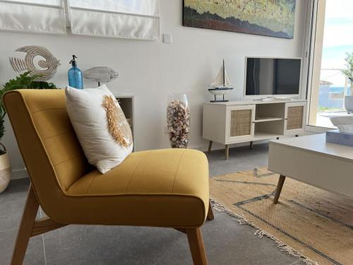 un salon avec une chaise jaune et une télévision dans l'établissement CORAL - Lumineux appartement Cap d'agde vue mer , idéalement situé, au Cap d'Agde
