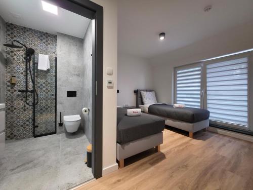 a bedroom with two beds and a shower and a bathroom at W64 Apartamenty in Płock