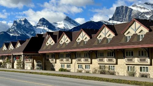 a hotel with snow covered mountains in the background at Canmore Inn & Suites in Canmore