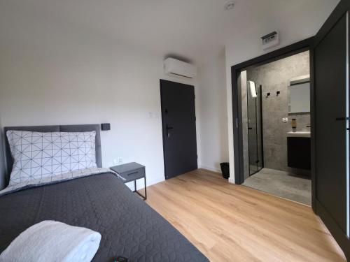 a bedroom with a bed and a door to a bathroom at W64 Apartamenty in Płock