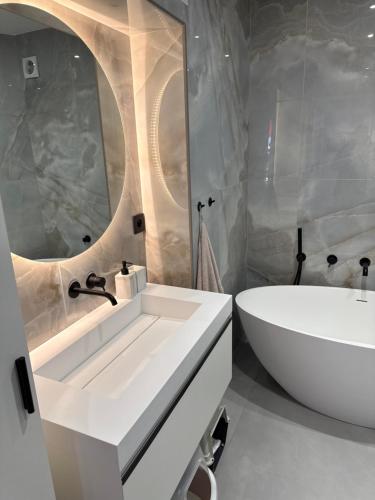 La salle de bains est pourvue d'un lavabo blanc, d'une baignoire et d'une chambre. dans l'établissement Terrasse tour, à Paris