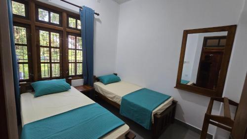 two beds in a room with a mirror and windows at Ramiy Resort Batticaloa in Batticaloa