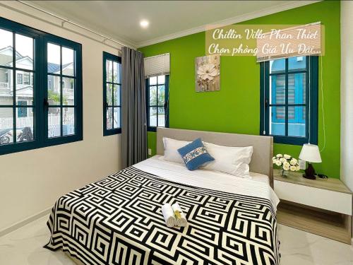 a bedroom with a bed with green walls and windows at Chillin Villa Novaworld Phan Thiet in Bình Tú