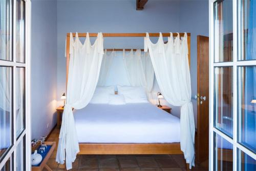 a bedroom with a canopy bed with white curtains at Atrio in Estreito da Calheta