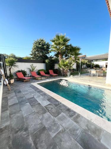 - une piscine avec des chaises rouges à côté d'une maison dans l'établissement Jolie villa sa piscine et ses 4 chambres, à Puget-sur Argens