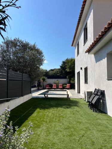 une cour avec des chaises et un banc à côté d'un bâtiment dans l'établissement Jolie villa sa piscine et ses 4 chambres, à Puget-sur Argens