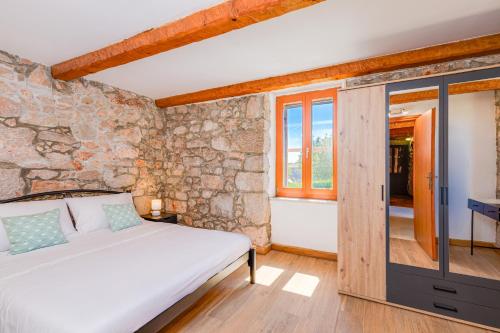 a bedroom with a bed and a stone wall at Villa Dora - family house with saltwater pool in Gostinjac, Krk Island in Gostinjac