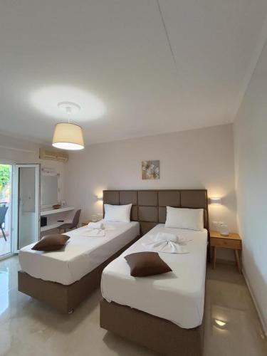 a bedroom with two beds and a kitchen with a table at Roussa's Apartments in Laganas