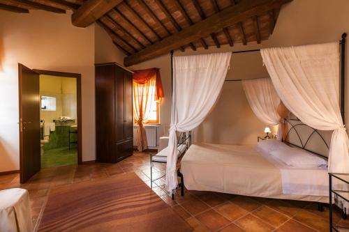 - une chambre dotée d'un lit avec des rideaux blancs dans l'établissement Il Conte Matto, à Trequanda
