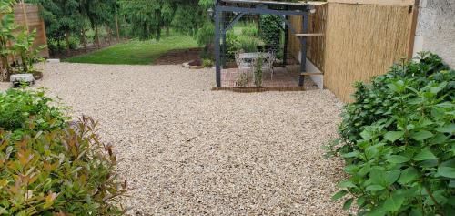 a gravel yard with a bird feeder in a garden at Gîte du Lavoir in Préaux