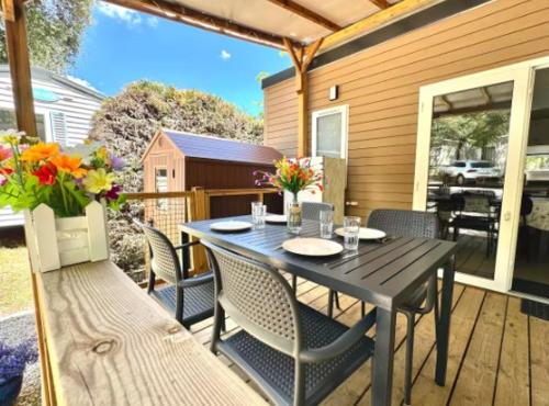 une table noire et des chaises sur une terrasse avec une table et des fleurs dans l'établissement Ruoms Mobil-home camping animé près des Gorges, à Lagorce