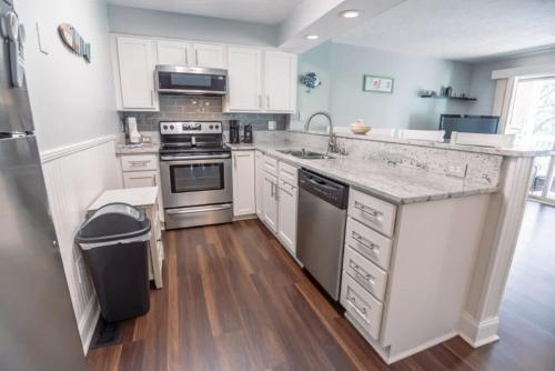 a kitchen with white cabinets and stainless steel appliances at Surfrider Beach Getaway in Kure Beach