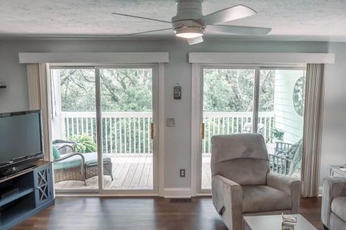 a living room with a ceiling fan and sliding glass doors at Surfrider Beach Getaway in Kure Beach