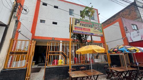 a restaurant with tables and umbrellas in front of a building at Pousada Freitas in Feira de Santana
