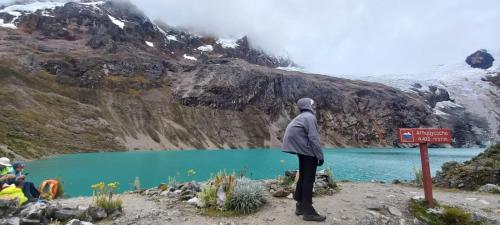 a person standing in front of a mountain lake at SANTA CRUZ TREKKING 4 DAYS from Vaqueria to Cashpampa purchase one night valued for 4 days trekking in Huaraz