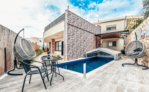 a backyard with a pool and two chairs and a table at Villa for families with a private pool in Daliyat El Carmel in Dāliyat el Karmil
