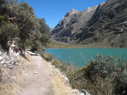 a dirt road next to a mountain lake at SANTA CRUZ TREKKING 4 DAYS from Vaqueria to Cashpampa purchase one night valued for 4 days trekking in Huaraz