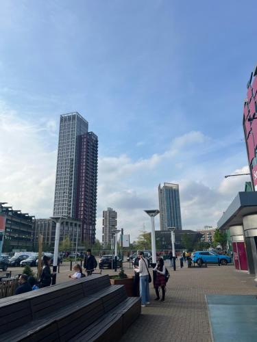 a group of people walking in a city with tall buildings at Large triple room in Canada Water London in London