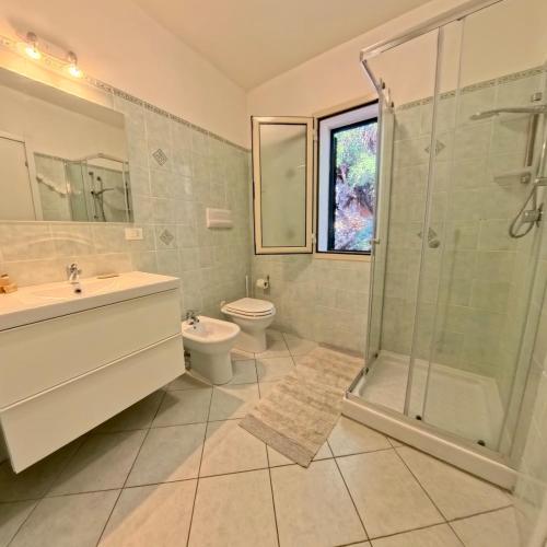 a bathroom with a shower and a sink and a toilet at Modern Seaview Townhouse - Workcation friendly in Orosei