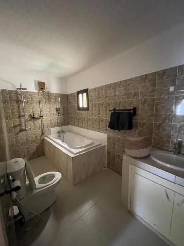 a bathroom with a tub and a toilet and a sink at Soleil ak Jàmm in Mbour