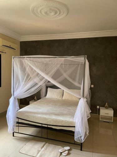 a white bed with a canopy in a bedroom at Soleil ak Jàmm in Mbour