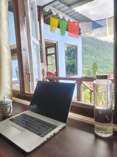 a laptop computer sitting on a table next to a window at The Blue House in Pelling