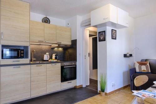- une cuisine avec des placards en bois et un four micro-ondes dans l'établissement Studio with balcony 50 m from the beach, à Sainte-Maxime