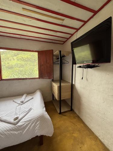 a room with a tv and a bed and a window at Finca La Macarena by Welttisch in Génova