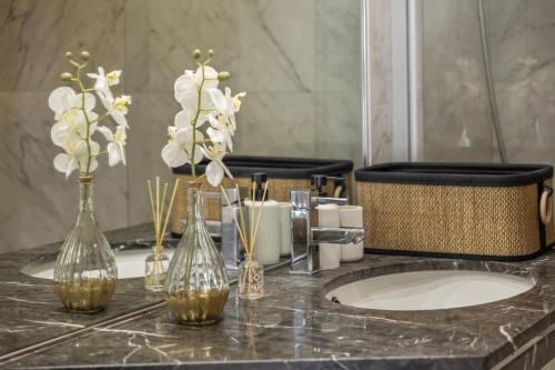 eine Badezimmerablage mit Vasen und Blumen darauf in der Unterkunft Forum Ocean View 5C by Homie in Ilhéu do Gorgulho