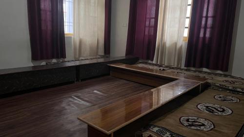 a living room with wooden floors and purple curtains at Gurmed Homestay by The Himalayan Abode in Kaza