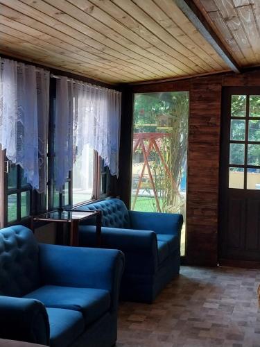 a living room with two blue couches and windows at Chácara Catavilela in Jacareí