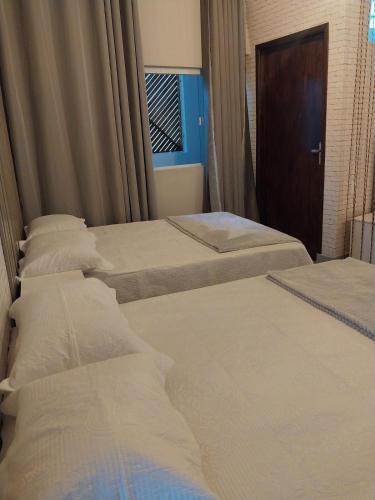 a row of three beds in a hotel room at Chácara Catavilela in Jacareí
