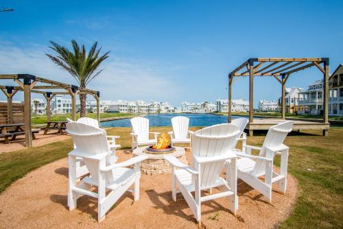 a group of white chairs sitting around a fire pit at Isle of Dogs 205FIV-B in Port Aransas