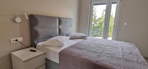 a bedroom with a large bed with a large window at Apartman Katarina in Brodarica