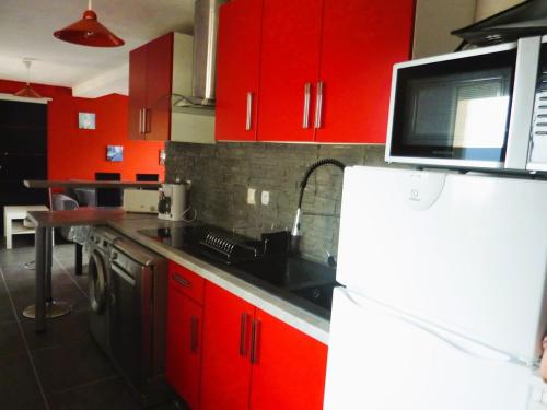 La cuisine est équipée de placards rouges et d'un évier noir. dans l'établissement Appartement front de mer Biarritz, à Biarritz