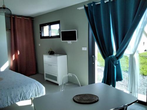 a bedroom with a bed and a table and a window at Charmant Studio climatisé 200m Voie verte, 500m des commerces in Ruoms