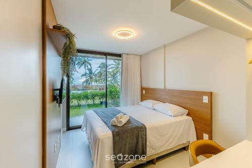 una stanza d'albergo con un letto e una finestra di Aptos em Cond. c/ piscina à Beira da Praia em Ilhéus - PET a Pontal