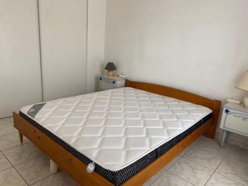 - un lit dans une chambre avec deux tables et un matelas dans l'établissement Appartement au centre-ville - Proche de la plage, à Valras-Plage