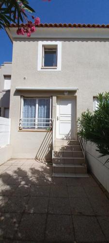 une maison blanche avec une porte et des escaliers blancs dans l'établissement Joli pavillon pour 6 personnes a 50m de la plage, à Valras-Plage